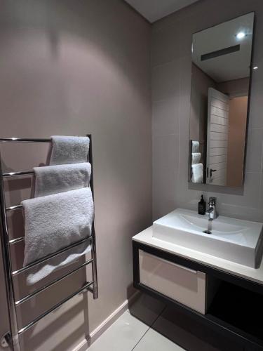 a bathroom with a sink and a mirror and towels at The Residences at Crystal Towers in Cape Town