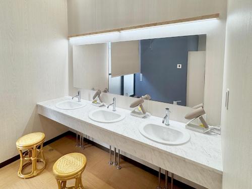 a bathroom with three sinks and a large mirror at Matsue Universal Hotel in Matsue
