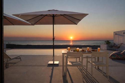 a table with an umbrella on a patio with the ocean at Azzurro Luxury Villas in Kolymbia