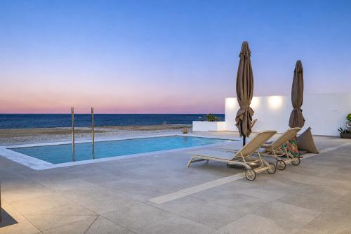 a swimming pool with two chairs and an umbrella at Azzurro Luxury Villas in Kolymbia