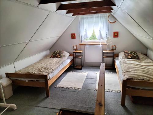 a attic room with two beds and a window at Zielony domek na Kaszubach in Raduń
