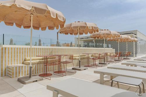 a row of tables and chairs under umbrellas on a patio at Intelier Malvarrosa Plaza in Valencia