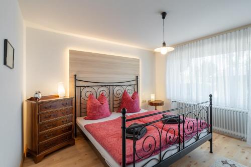 a bedroom with a bed with pink pillows and a dresser at Ferienwohnung Carolin in Dornstetten