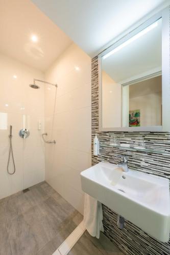 ein Badezimmer mit Waschbecken, Dusche und Spiegel in der Unterkunft Santana Hotel & SPA in St Paul's Bay