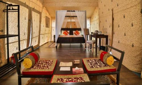 a room with a bed and a table and chairs at Sam Sand Dunes Camps Jaisalmer in Sām
