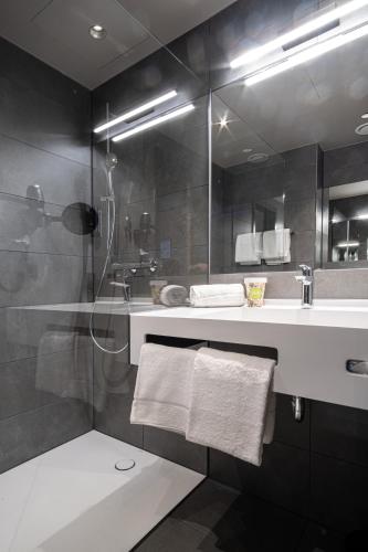 a bathroom with a shower and a sink and a mirror at RiKu Hotel Giengen in Giengen an der Brenz
