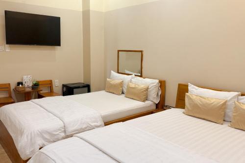 a hotel room with two beds and a flat screen tv at Đào Huỳnh Motel in Nam Du