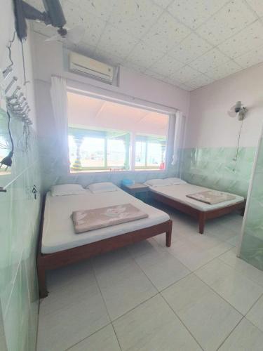 a room with two beds and a window at Đào Huỳnh Motel in Nam Du