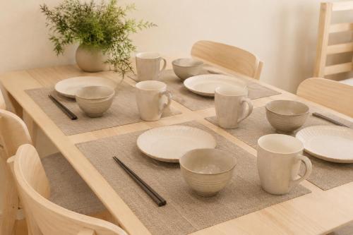 a wooden table with white plates and chopsticks on it at Dori Dori House Ebisu in Tokyo