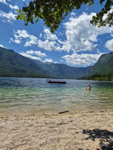 a person swimming in a lake with a boat in the water at Alpine Forest Apartments in Radovljica