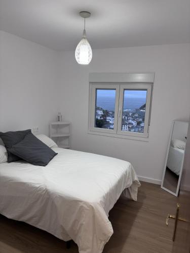 a white bedroom with a bed and a window at Casa La Peña in Luarca