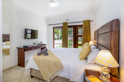 a bedroom with a bed and a desk and a window at Comfort on Cabot in Edenvale
