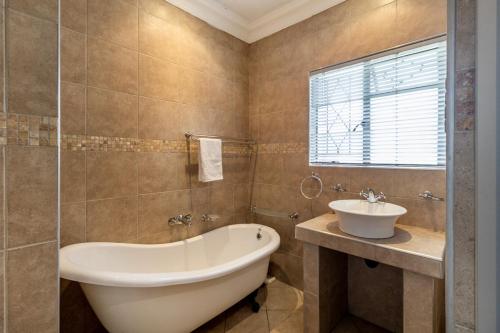 a bathroom with a tub and a sink at Comfort on Cabot in Edenvale