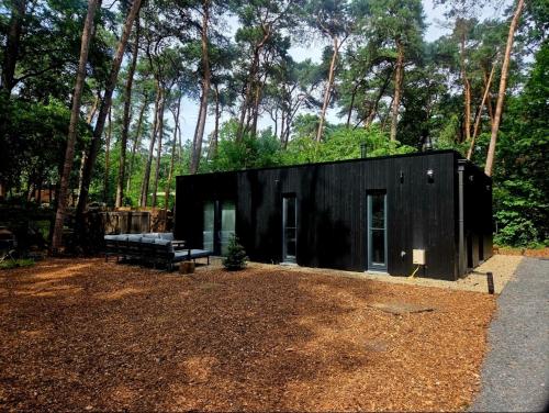 a black house with a bench and trees at Whispering Pines in Retie