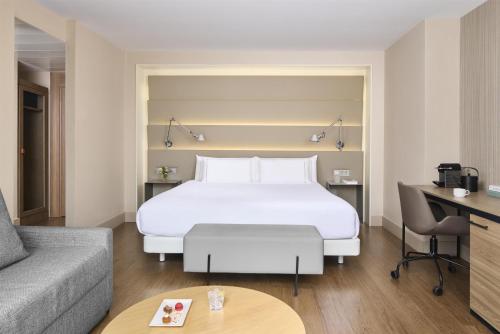 a hotel room with a large bed and a couch at NH Sants Barcelona in Barcelona