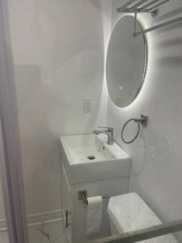 a white bathroom with a sink and a mirror at Oshawa Suite Open Kitchen Living Space in Oshawa