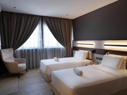a hotel room with two beds and a chair at Merchant Hotel in George Town