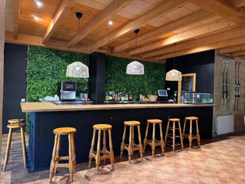 a bar with stools in front of a green wall at Hotel Casa Eira B&B in La Molina