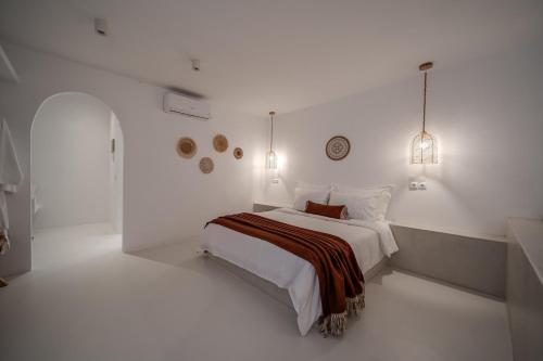 a white bedroom with a bed and two lights at Caldera's Elements in Santorini