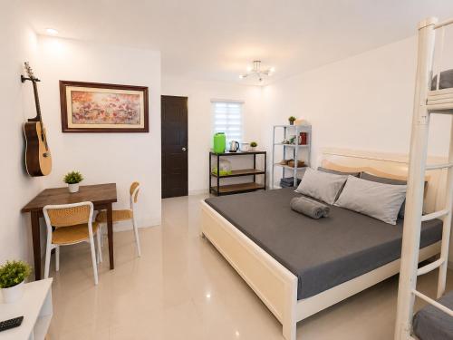ein Schlafzimmer mit einem Bett, einem Schreibtisch und einer Gitarre in der Unterkunft Harmony Villa in Tanza