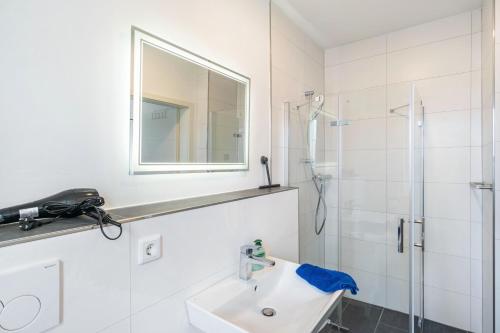 a white bathroom with a sink and a shower at Haus Seeluft - W4 in Butjadingen