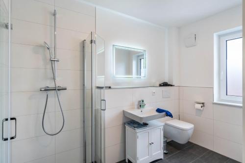 a white bathroom with a shower and a sink at Haus Seeluft - W5 in Butjadingen