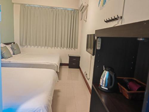 a hotel room with two beds and a television at 浮雲澗民宿 in Hu-hsia