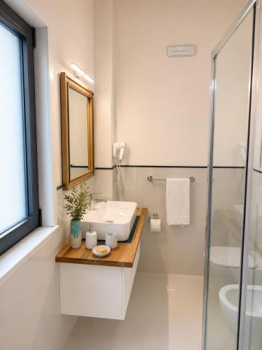 a white bathroom with a sink and a shower at The Queen Oak - nature relais in Santa Marina