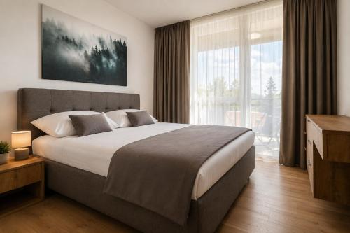 a bedroom with a large bed and a large window at Evergreen Tale Apartman F2 in Tale