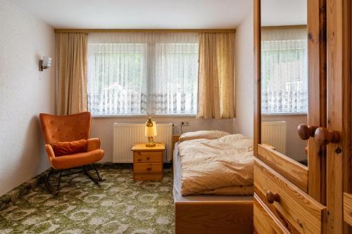 a bedroom with a bed and a chair and windows at Ferienhaus Adelheid in Bad Grund