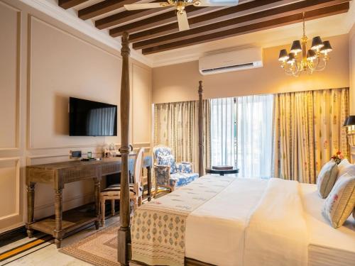 a bedroom with a bed and a desk and a television at Panna Vilas - A Lake Facing Boutique Hotel in Udaipur