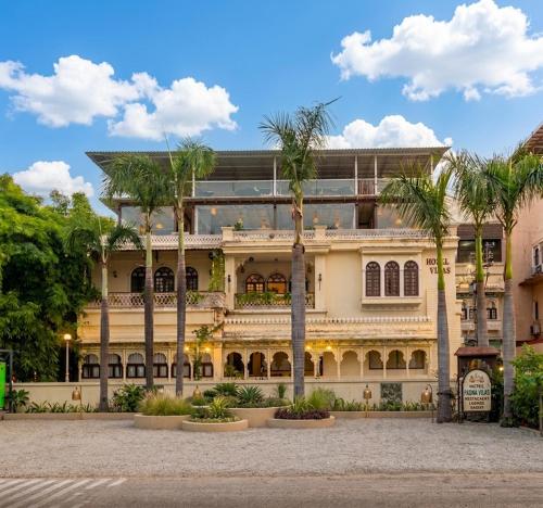 a large building with palm trees in front of it at Panna Vilas - A Lake Facing Boutique Hotel in Udaipur