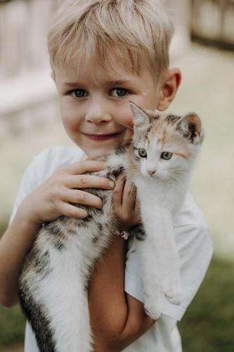 a young boy holding a cat in his arms at Lerchs Landhotel in Sankt Johann im Pongau