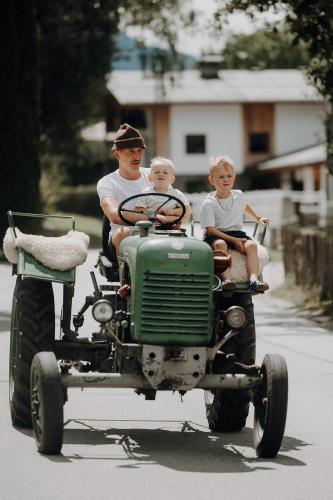 a man and two boys riding on an old tractor at Lerchs Landhotel in Sankt Johann im Pongau