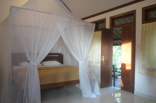 a bedroom with a canopy bed with white curtains at Kangkung Cottages in Jasri