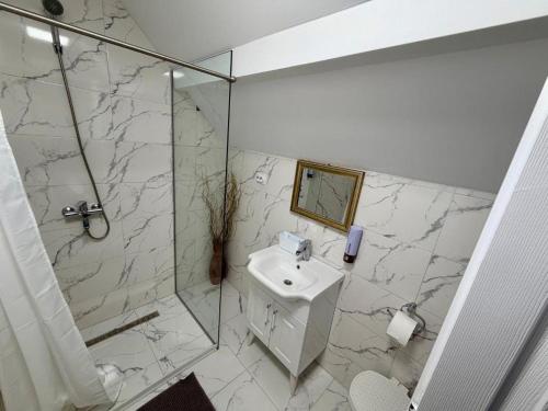 a white bathroom with a sink and a shower at Casa cu Dor in Odăile