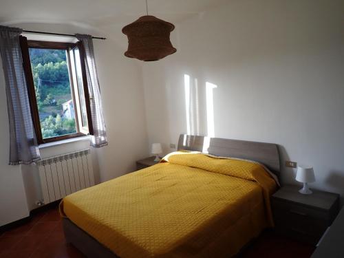 a bedroom with a yellow bed and a window at Nidus in Aulla