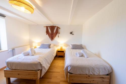 two beds in a room with white walls and wooden floors at Gîte L'instant Vosges in Aydoilles