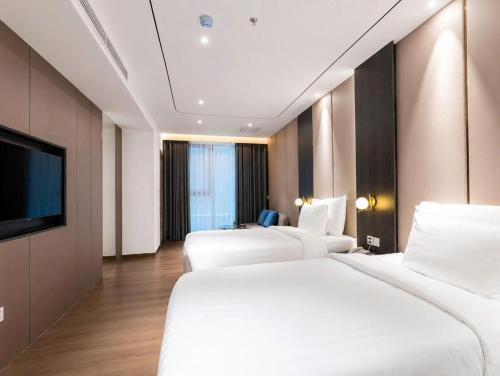 a hotel room with two beds and a flat screen tv at Sunshine Grand Hotel in Móng Cái