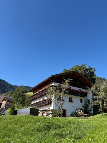 a white building with a wooden roof on a green field at Pardellerhof Lüsen in Luson