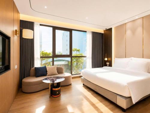 a bedroom with a bed and a couch and a window at Sunshine Grand Hotel in Móng Cái