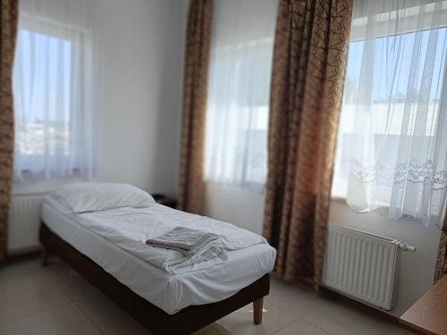 a small bed in a room with windows at Hostel Wólka Kosowska z prywatnymi łazienkami in Wólka Kosowska
