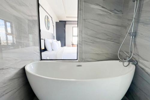 a white tub in a bathroom with a mirror at Sandals Everyday Hotel in Tuy Hoa