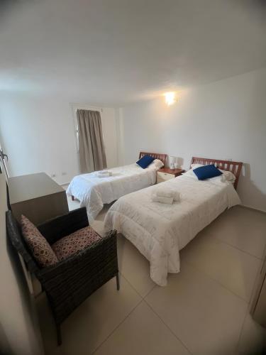 two beds in a room with a chair and a couch at Cormorani appartamento N 5 in Golfo Aranci