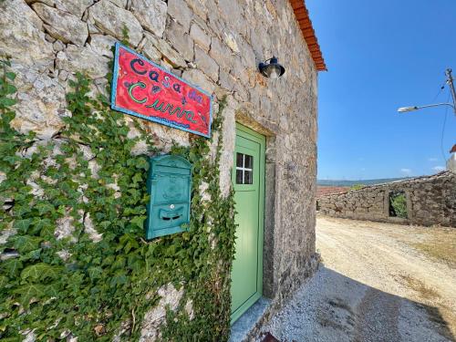 a building with a green door and a sign on it at Casa da Curva in Mendiga