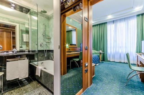 a bathroom with a tub and a sink and a room at Brunelleschi Hotel in Milan