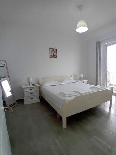 a white bedroom with a bed and a mirror at Mimi's Apartments, Palasë in Palasë