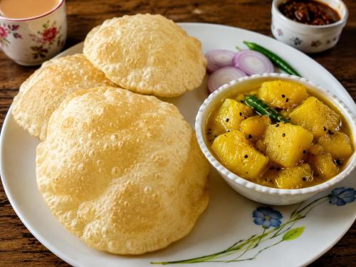 a plate with a plate of food with a bowl of curry at Hotel Kasol Heritage in Lucknow