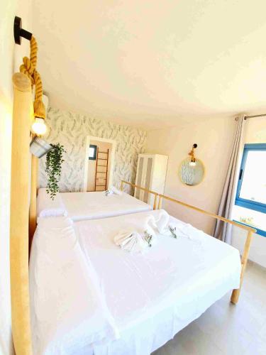 a bedroom with a bed with white sheets and a window at B&B La Nava Suites in Mojácar