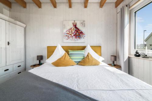 a bedroom with a large white bed with yellow pillows at Ferienhaus Möwenkoje Olpenitz in Olpenitz
